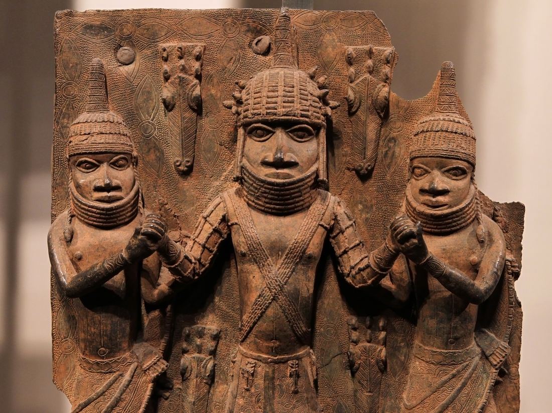 A brass plaque from the Kingdom of Benin with figures carrying weapons and regalia
