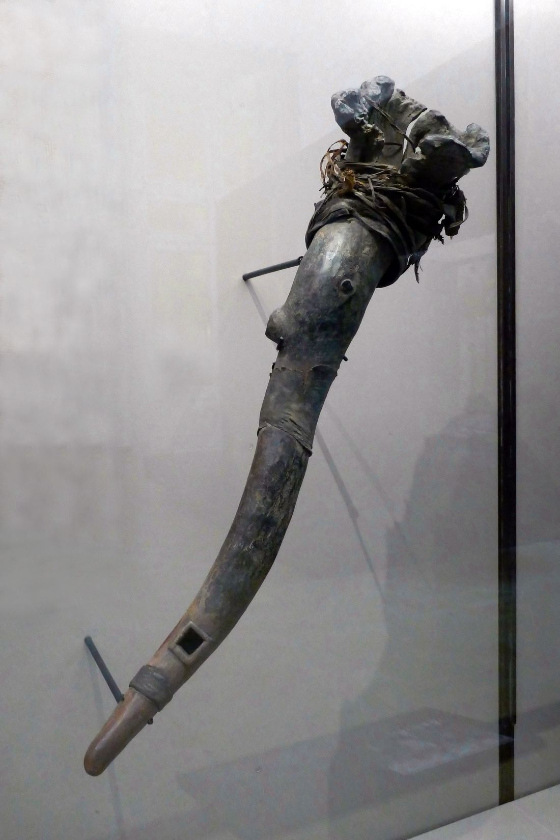 A wooden dondo hourglass drum with leather cords displayed in a museum